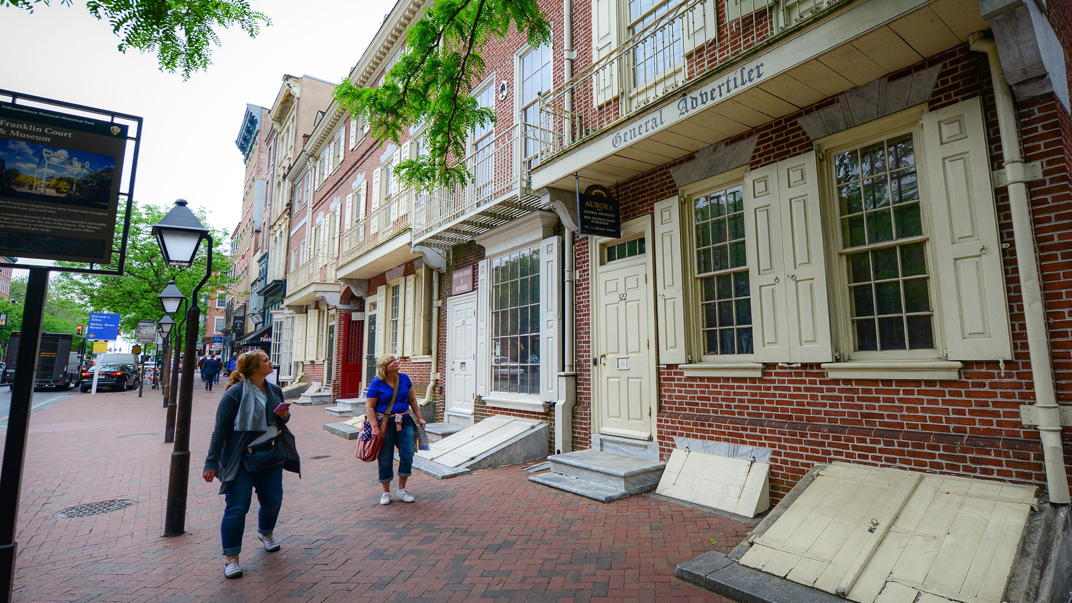 Les visiteurs se promènent le long de Market Street, longeant des bâtiments historiques en briques aux volets couleur crème, parmi lesquels l'imprimerie de Benjamin Franklin.