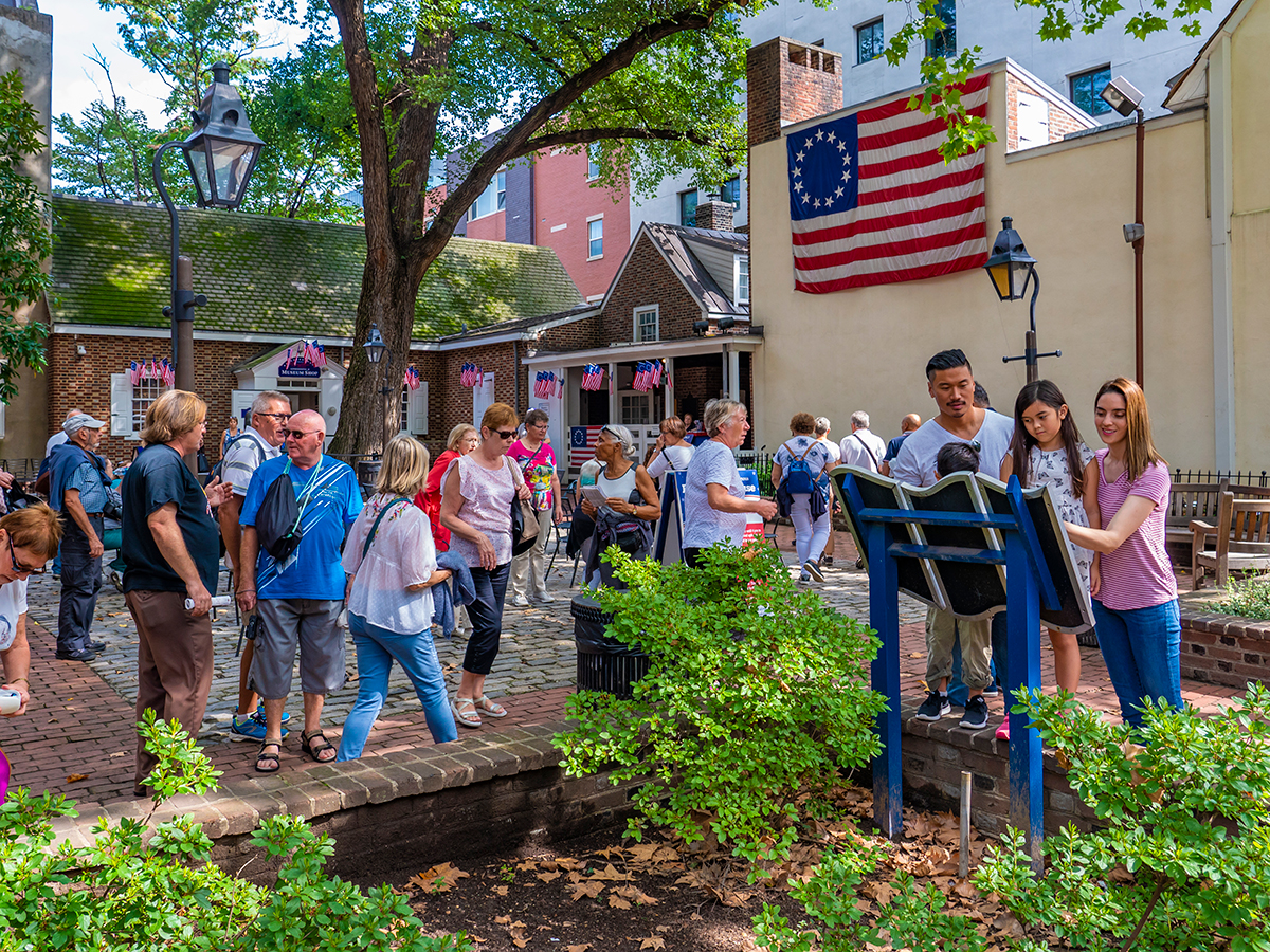 Visitors explore the courtyard at the Betsy Ross House, where America's first flag hangs from colonial era-buildings.
