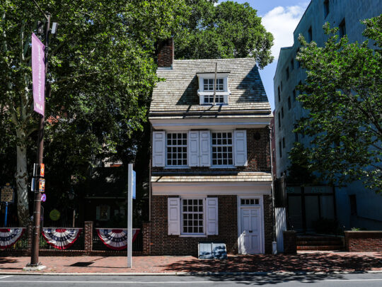 Vue de face de la maison Betsy Ross, une demeure coloniale de deux étages parfaitement conservée, dotée de volets blancs et d'une porte d'entrée.