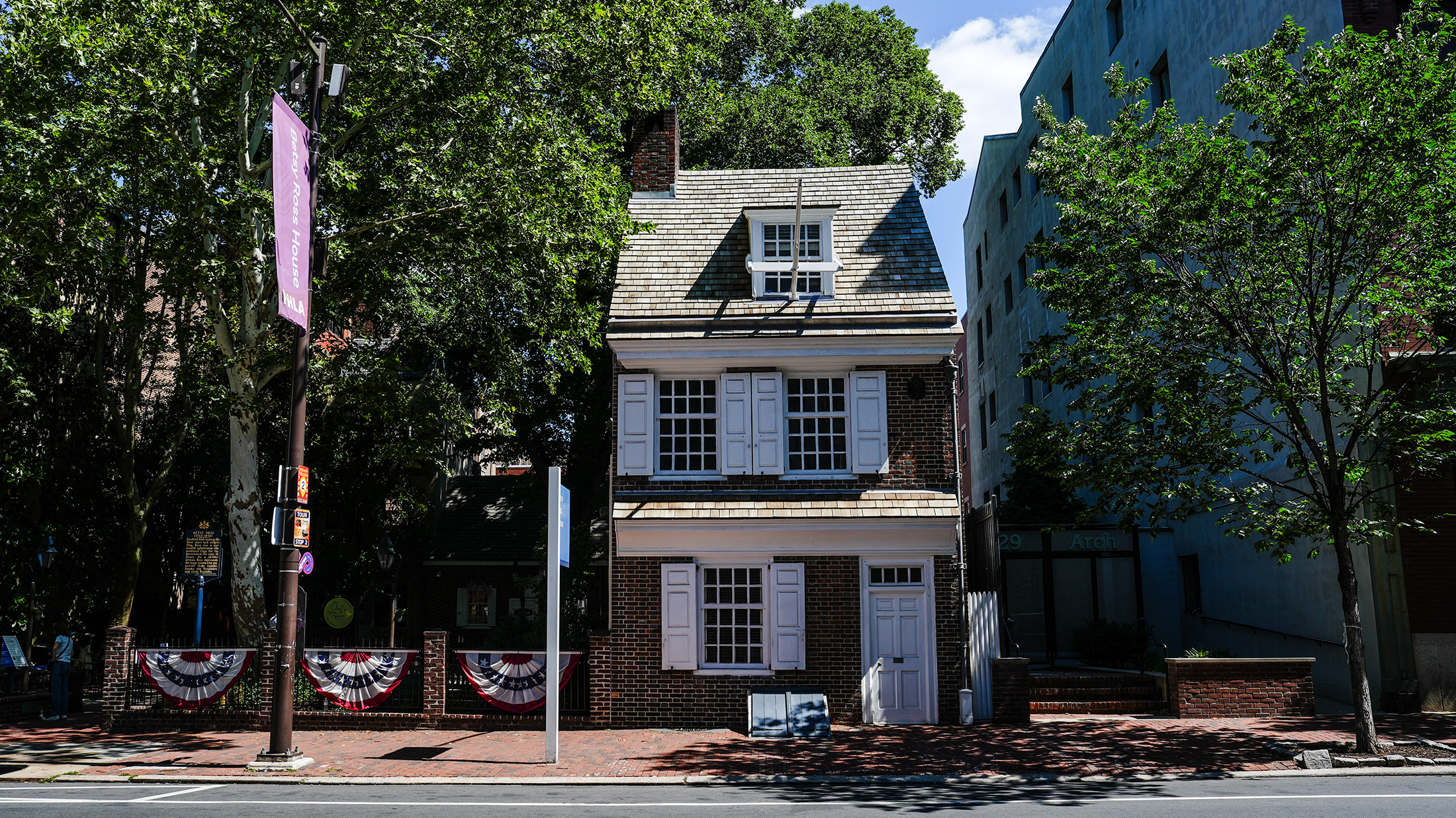 Vue de face de la maison Betsy Ross, une demeure coloniale de deux étages parfaitement conservée, dotée de volets blancs et d'une porte d'entrée.