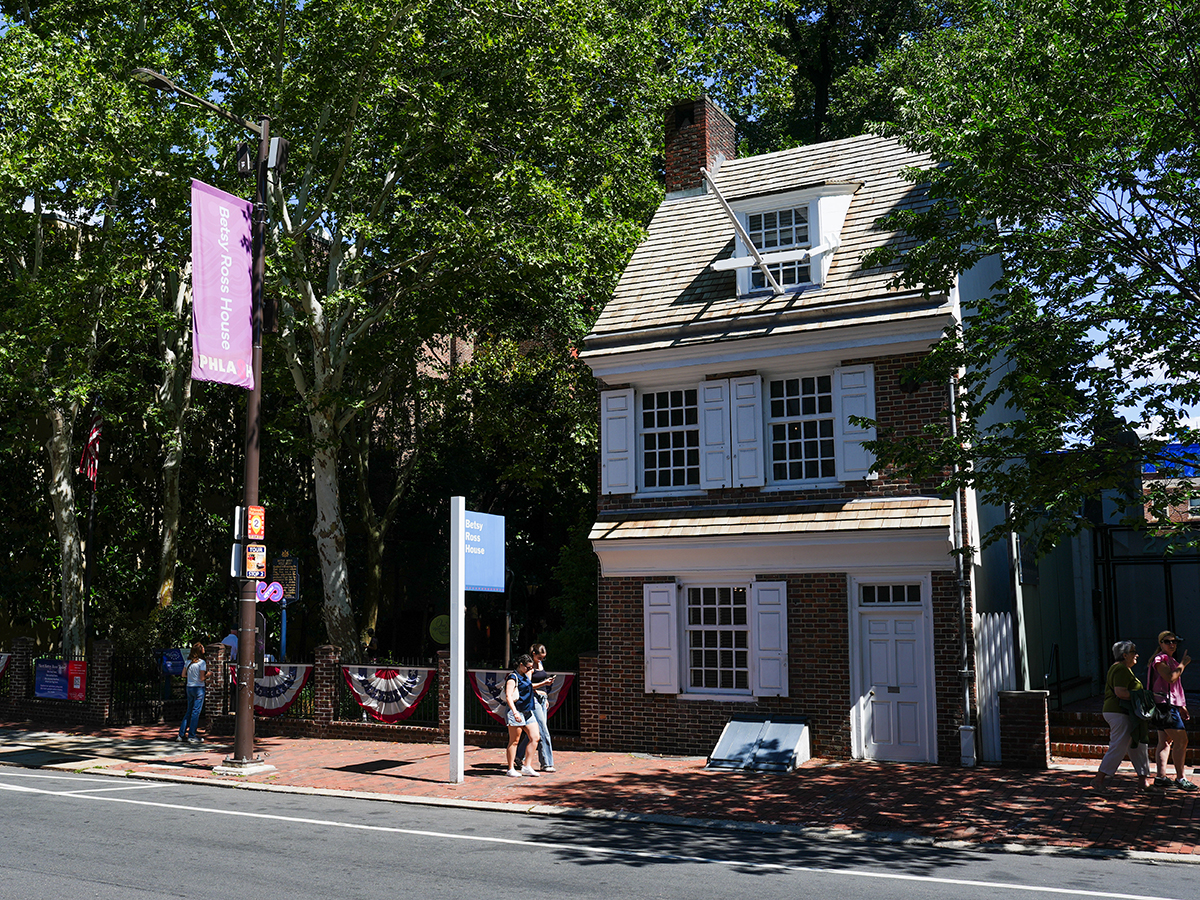 Vue de face de la maison Betsy Ross, une demeure coloniale de deux étages parfaitement conservée, dotée de volets blancs et d'une porte d'entrée.