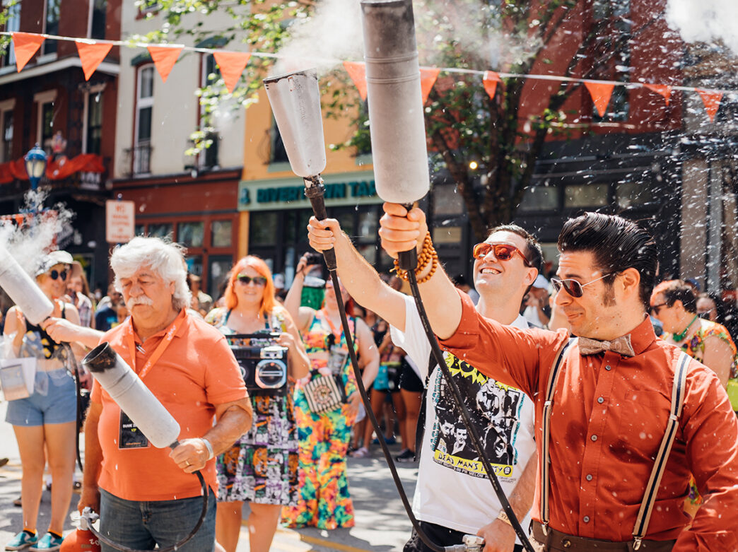 Participants point fire extinguishers into the air during a street parade at the Colonial Theatre's BlobFest.