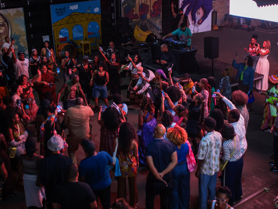 Festivalgoers dance in a circle beneath colorful lights during an opening night party at the BlackStar Film Festival.