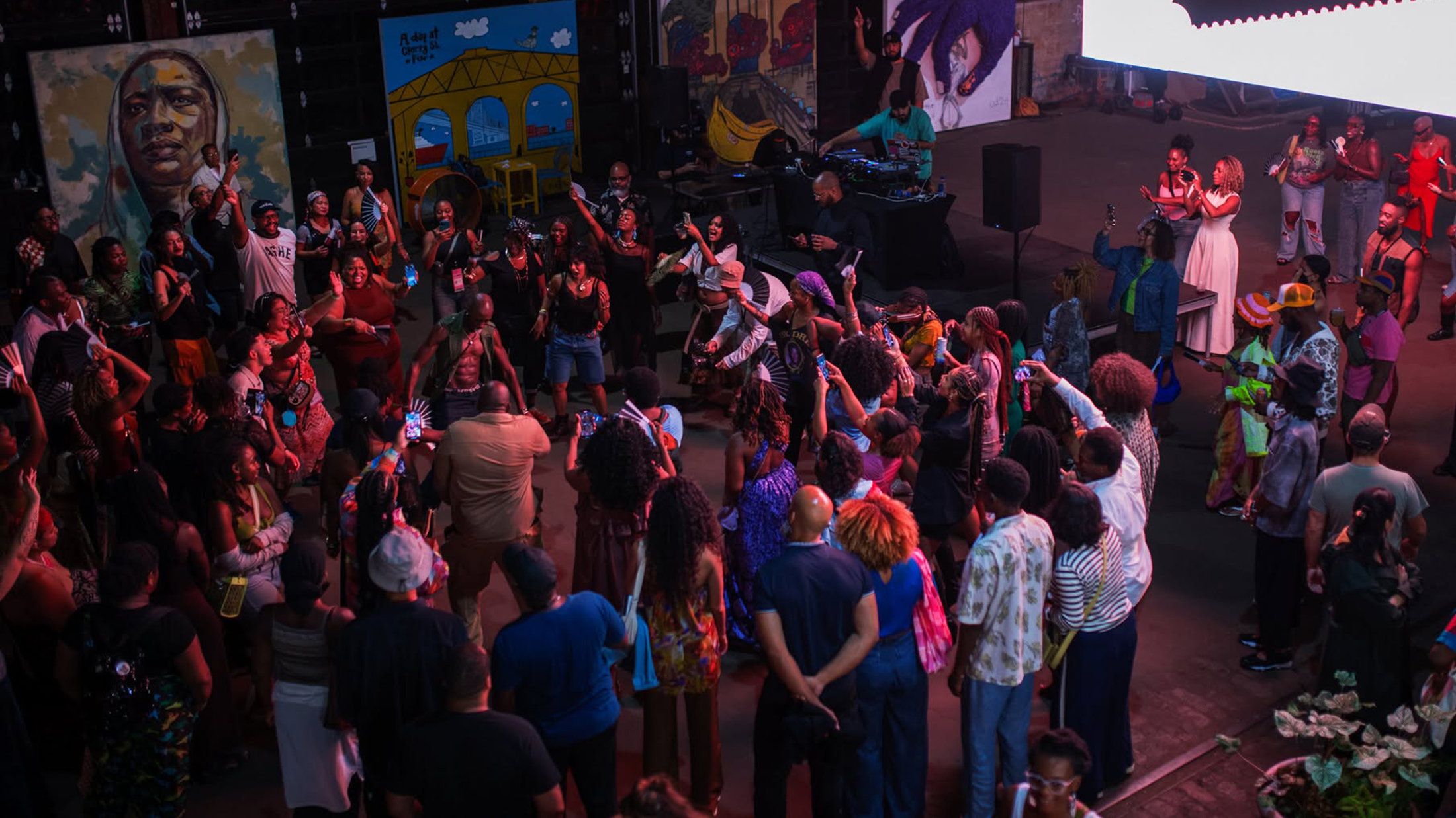 Festivalgoers dance in a circle beneath colorful lights during an opening night party at the BlackStar Film Festival.