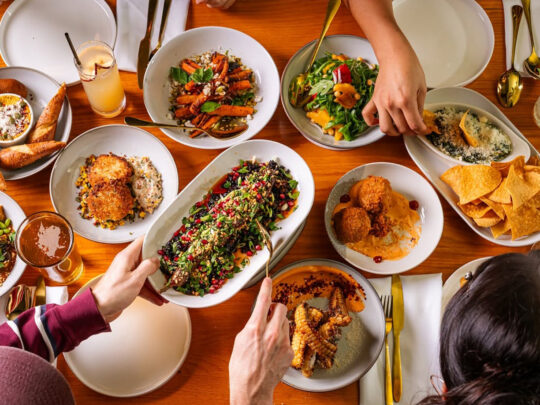 An overhead view of colorful shareable dishes, including salads, appetizers, roasted vegetables and cocktails, spread across a table at Fitz on 4th in Philadelphia.