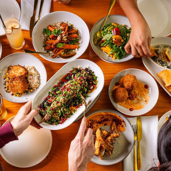 Una vista aérea de coloridos platillos para compartir, que incluyen ensaladas, aperitivos, verduras asadas y cócteles, dispuestos sobre una mesa en el restaurante Fitz on 4th de Filadelfia.