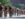 A pack of professional cyclists wearing helmets, sunglasses and cycling jerseys races down the Benjamin Franklin Parkway during the Philadelphia Cycling Classic.
