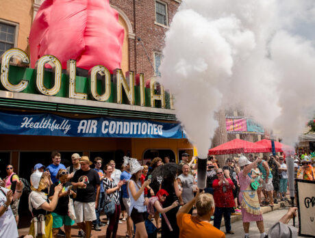 Une foule s'est rassemblée devant le Colonial Theatre à l'occasion du BlobFest de Phoenixville, tandis que des participants vêtus de costumes colorés pulvérisaient de l'eau avec des extincteurs en l'air lors du défilé emblématique du festival, avec en arrière-plan la marquise emblématique du théâtre.