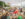 People eat at a table full of food and drinks, women sit on a colorful hammock and a crowd of people walk along the waterfront at Spruce Street Harbor Park.