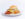 A buttermilk biscuit breakfast sandwich with bacon, eggs and melted cheese sits on a white plate, garnished with chopped parsley.