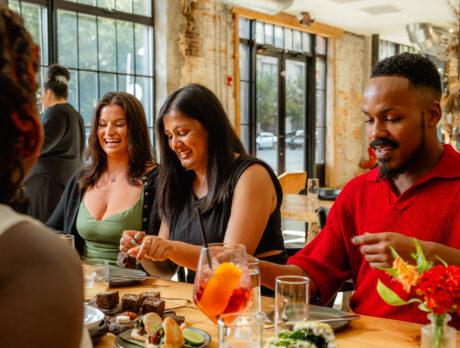 Diners gather around a wooden table, sharing small plates and conversation inside Honeysuckle's light-filled dining room.