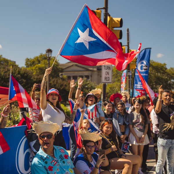 A lively crowd cheers and waves Puerto Rican flags along the Benjamin Franklin Parkway during Philadelphia's Puerto Rican Day Parade.