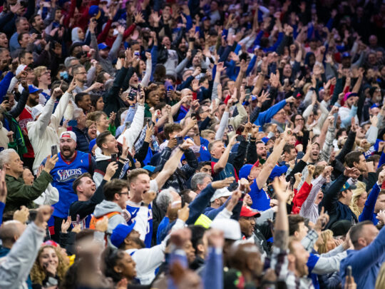 Sixers fans — many dressed in blue Sixers jerseys and T-shirts — go wild in the stands.