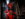 A costumed performer with a gory red mask, tattered red clothing and a glowing lantern lurks in a dark corridor at Eastern State Penitentiary.