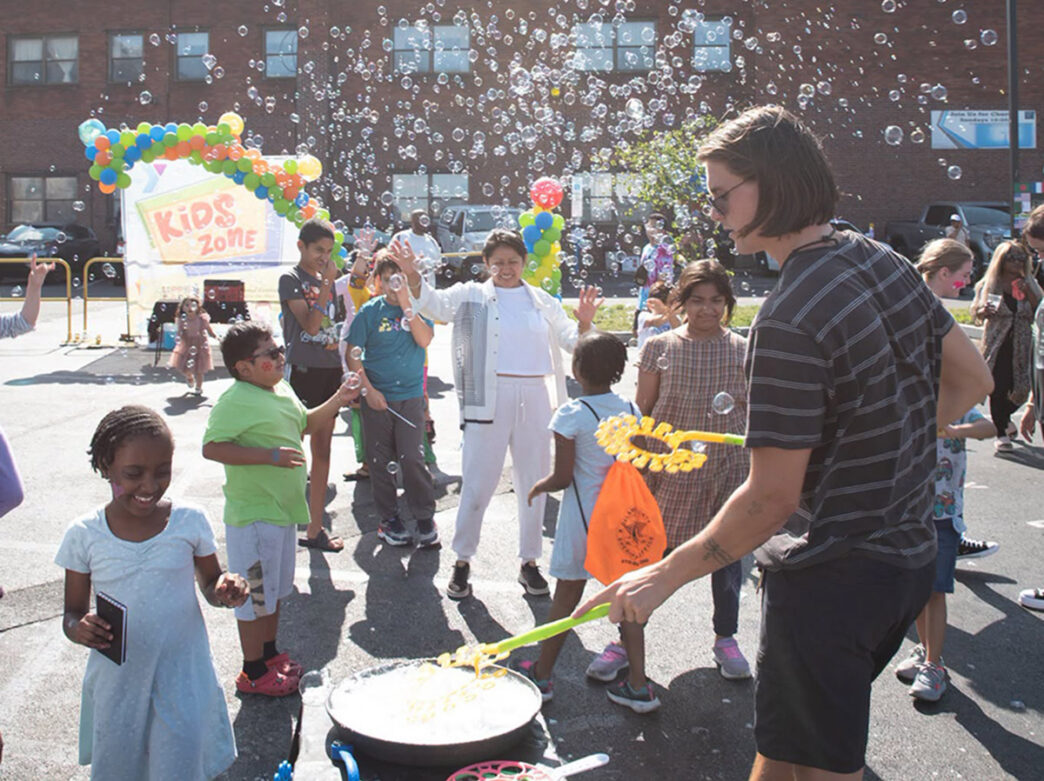 A group of kids smile and play among a sea of bubbles.