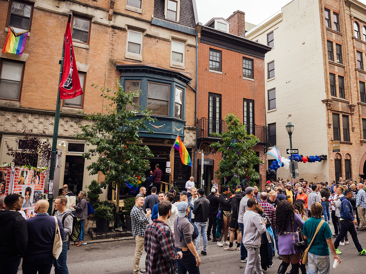Crowds gather in a car-free street decorated with pride flags at the annual Ourfest celebration.