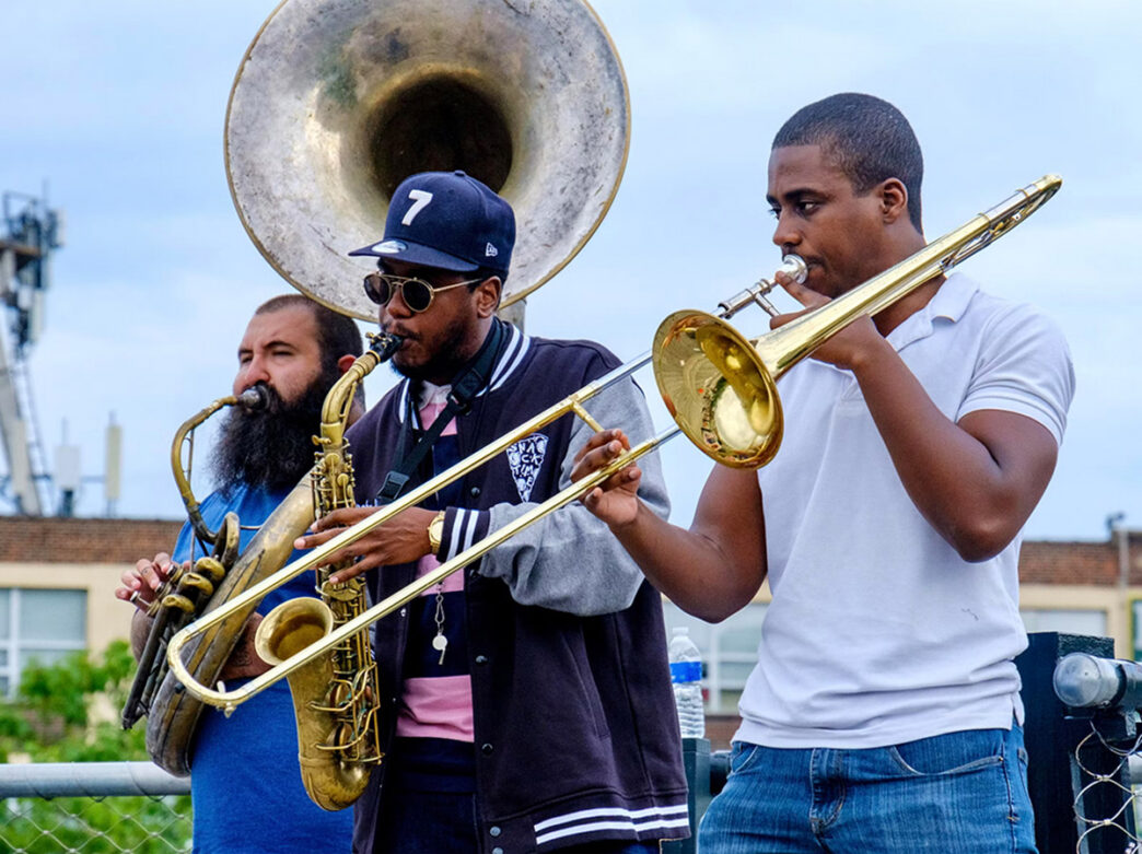 Musicians play the tuba, saxophone and trombone.