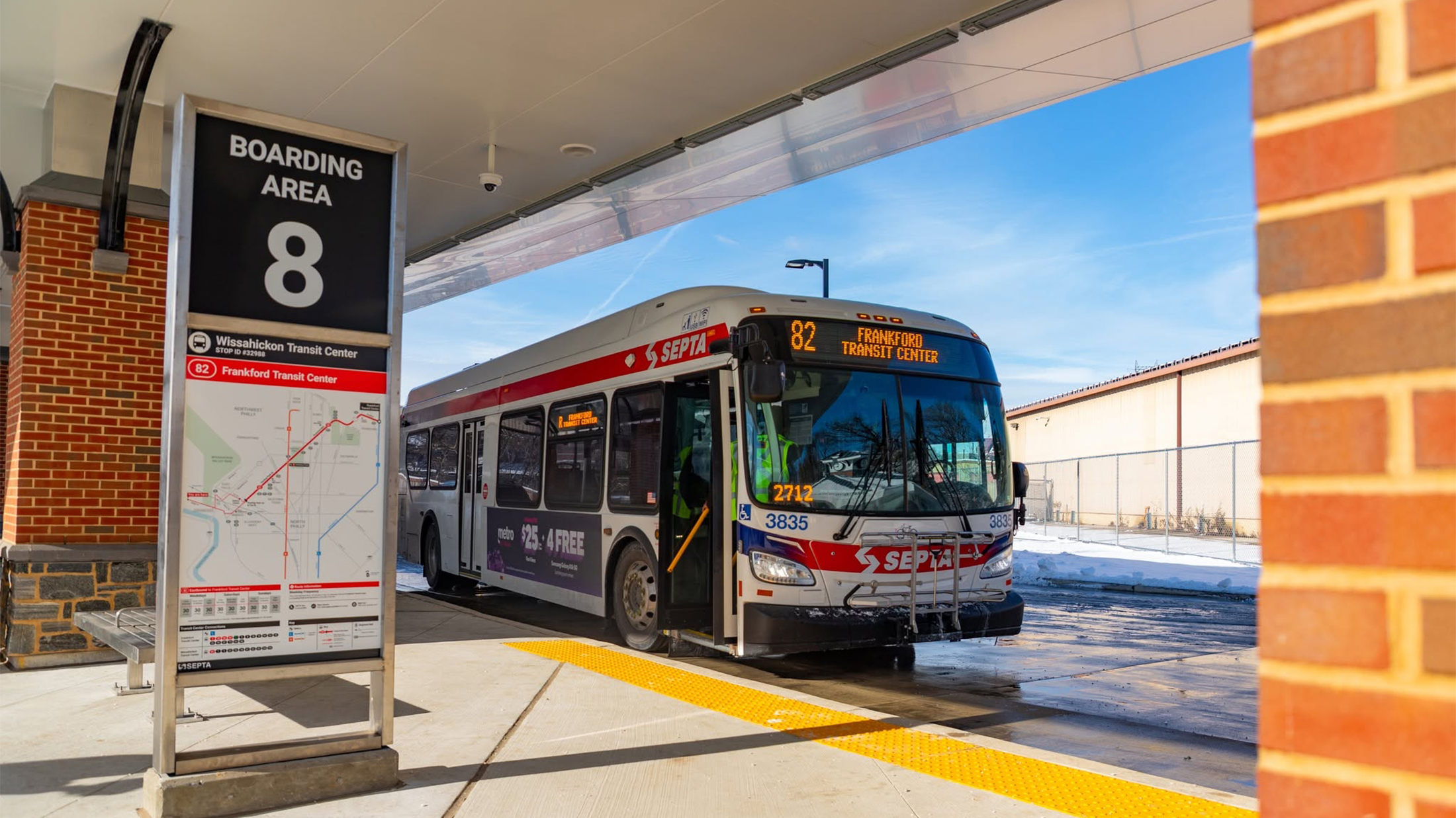 A SEPTA Route 82 bus bound for Frankford Transit Center waits at a boarding area on a sunny winter day.
