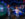 Two excited kids run hand-in-hand through a dark, blue-lit space exhibit filled with colorful interactive displays about planets and wavy LED lights.