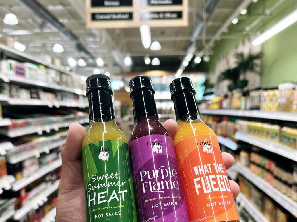 Three bottles of FAIYA hot sauce are displayed prominently in a grocery store aisle.