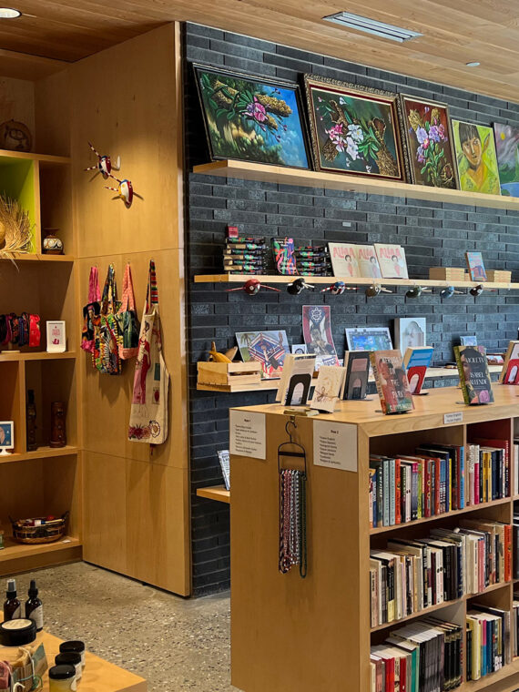 Inside the Julia de Burgos Bookstore at Taller Puertorriqueño. Books are displayed on shelves, with other products nearby