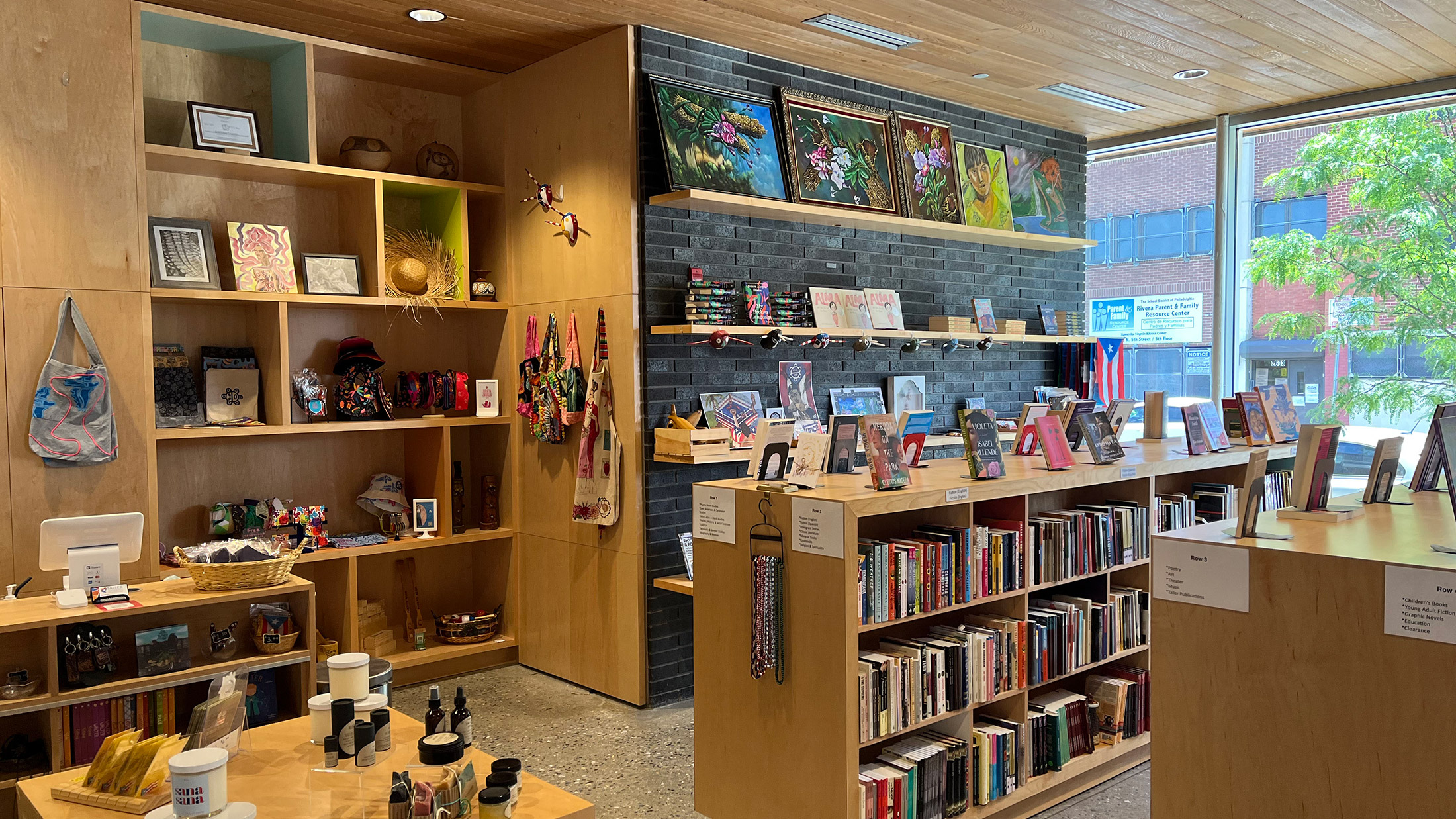 Inside the Julia de Burgos Bookstore at Taller Puertorriqueño. Books are displayed on shelves, with other products nearby