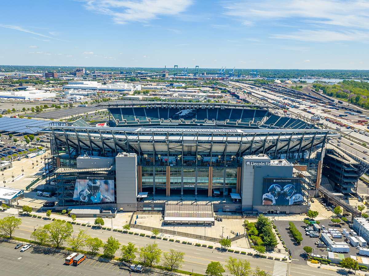An aerial view of Lincoln Financial Field, home of the Philadelphia Eagles, showing the stadium, surrounding parking lots and South Philadelphia landscape under a blue sky.
