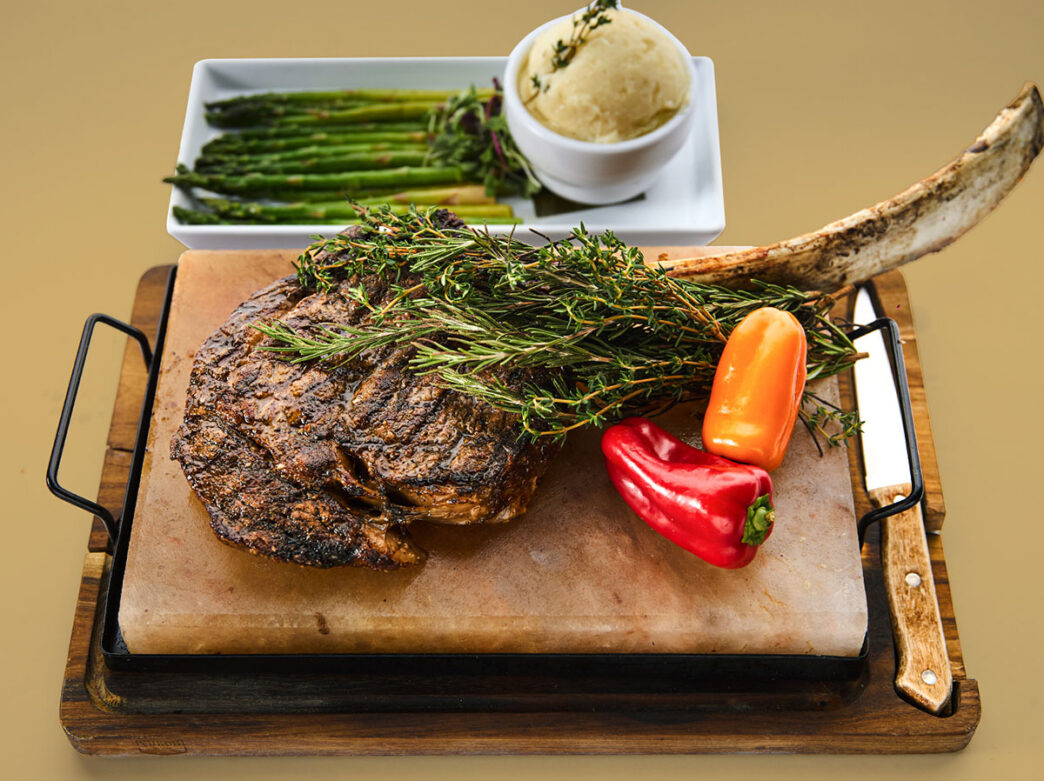 A tomahawk steak gets served on a butcher's board at Mamajuana Cafe Philly.