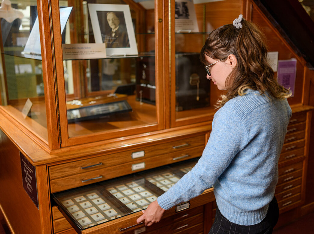 A visitor opens a drawer of specimen slides in a wooden display case at Philadelphia’s Mütter Museum.