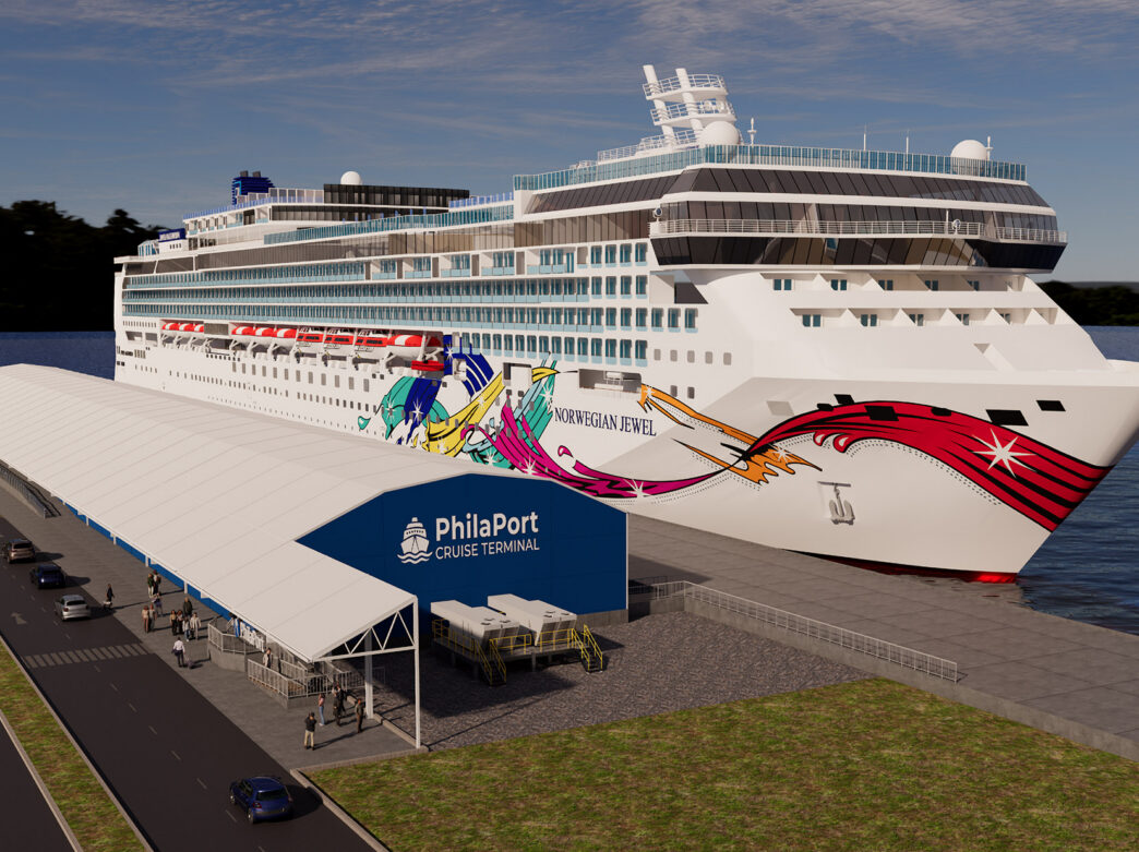 Vue d'ensemble du paquebot de croisière « Norwegian Jewel », aux couleurs vives, amarré à côté du nouveau terminal de croisière PhilaPort sur le fleuve Delaware, avec une passerelle couverte pour les passagers et des véhicules à l'extérieur du terminal.