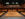 Un moderno auditorio de teatro con butacas de color beige dispuestas en gradas, un balcón superior y cálidas paredes revestidas de paneles de madera, visto desde el escenario.