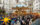 Visitors explore rows of wooden holiday market stalls decorated with glowing lights and star shaped ornaments, with a colorful Ferris wheel in the center.