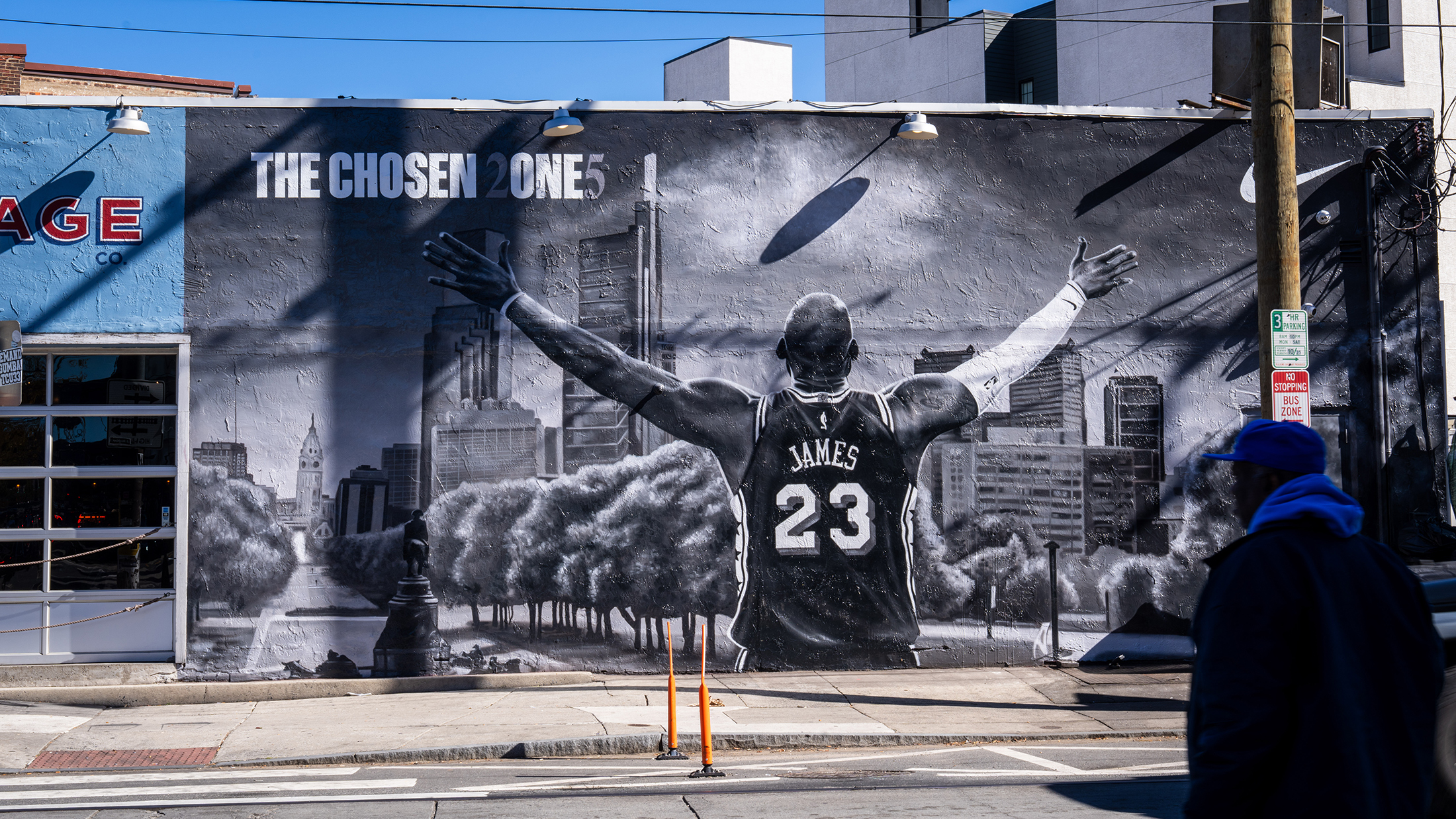 A black-and-white mural of LeBron James wearing his number 23 jersey with arms outstretched covering the side of a building in Philadelphia.
