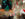 Visitors gather inside a historic building to enjoy the annual holiday light show, featuring a towering glowing Christmas tree, surrounded by illuminated reindeer and festive decorations.
