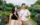 A smiling couple strolls hand in hand along a brick pathway at Longwood Gardens, surrounded by colorful flowers, lush greenery and vibrant seasonal blooms.