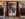 A retro-inspired lounge featuring walls covered in vintage concert posters, large speakers, patterned tile floors and a cozy seating area with pink chairs, a blue sofa and fireplace.