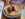 A close up image of a Belgium waffle topped with crispy fried chicken as syrup is poured over the dish.